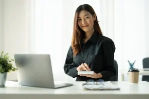 Office professional working with business records at a desk with a laptop and notebook