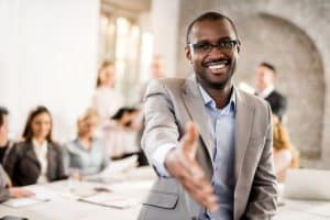 Business professional extending a handshake during a meeting with colleagues